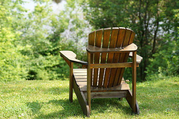 istock Adirondack Chair on lush green lawn with trees 518917403