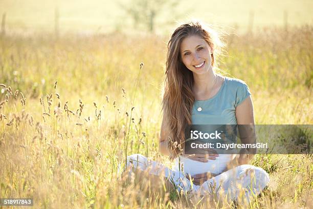 Pregnant Woman Sitting In Sunshine And Meadow Stock Photo - Download Image Now - 20-29 Years, Abdomen, Adult