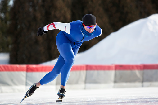 A male athlete speed skating on a cold winter day.