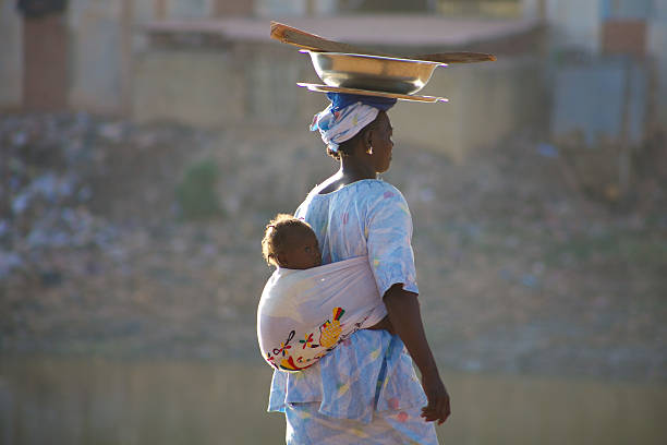 African Woman carrying a baby in Mopti Mopti, Mali - December 26, 2010: Unidentified black African woman carrying a baby in her back in the streets of Mopti. 2010 Mali stock pictures, royalty-free photos & images