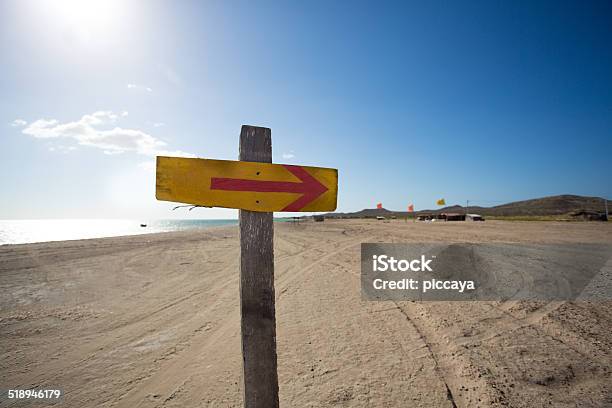 Wooden Sign With Arrow And Beach In The Background Stock Photo - Download Image Now - Arrow Symbol, Traffic Arrow Sign, Beach