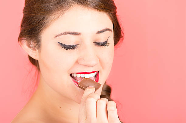 istock pretty young girl eating chocolate 518948873
