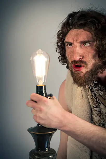 Silly realistic caveman dumbfounded by confusing edison lightbulb