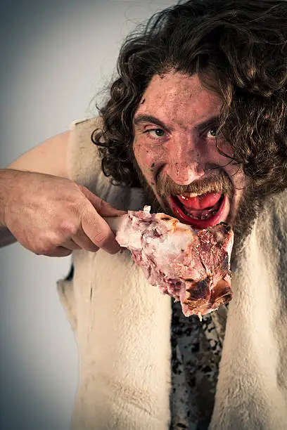 Silly hungry cave man eating ham on the bone