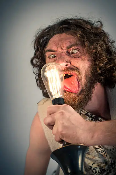 Silly realistic caveman dumbfounded by confusing edison lightbulb
