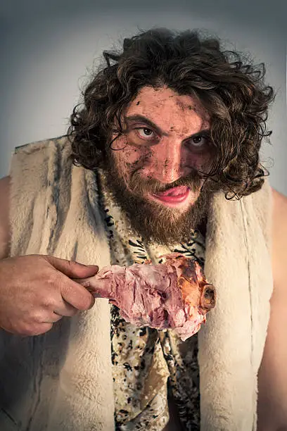 Silly hungry cave man eating ham on the bone