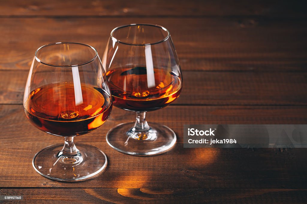 Two glasses of cognac on the wooden table. Brandy Stock Photo