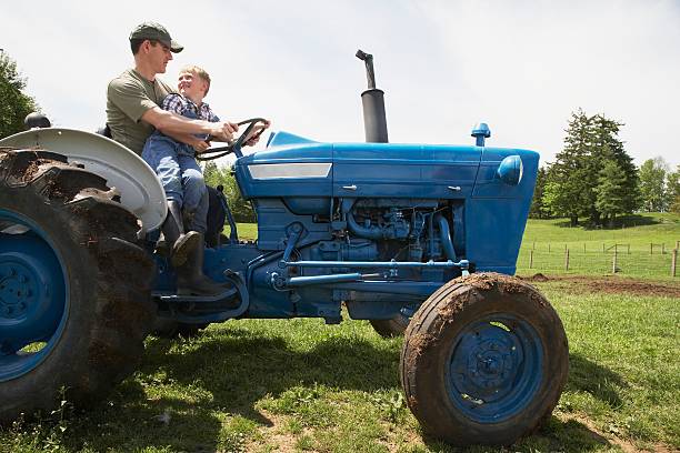 padre e figlio in sella a trattore in fattoria - farmer farm family son foto e immagini stock