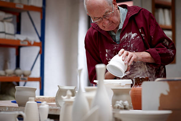 istock Senior potter painting wet clay pot 518978045
