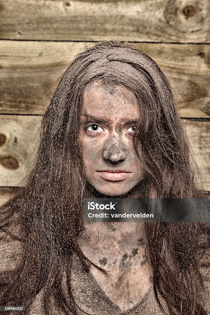 Lunatic Victorian-style lunatic - covered in filth and wearing a dress made from sackcloth. Wood ash is raining down on her. 20-24 Years Stock Photo