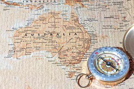 Compass on a map pointing at Australia, planning a travel destination