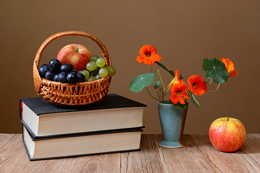 Fresh fruit in the of basket wicker, books and flowers in a vase