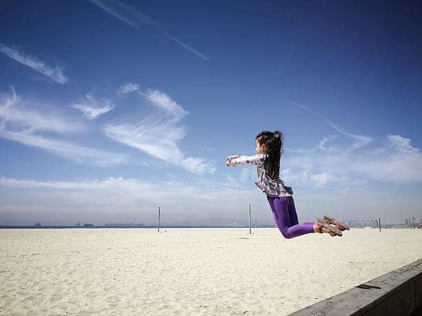 幸せな少女空のジャンプの空のビーチ - mobilestock usa sparse child ストックフォトと画像