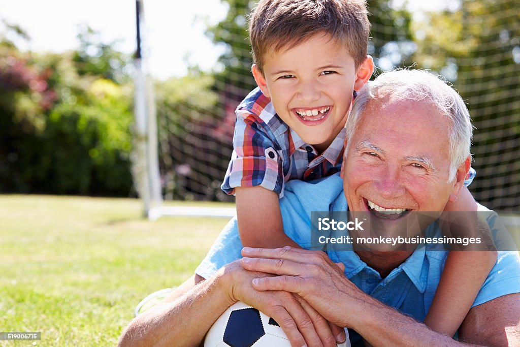 Portrait Of Grandfather And Grandson With Football Portrait Of Grandfather And Grandson With Football Lying On The Grass Smiling To Camera Soccer Stock Photo