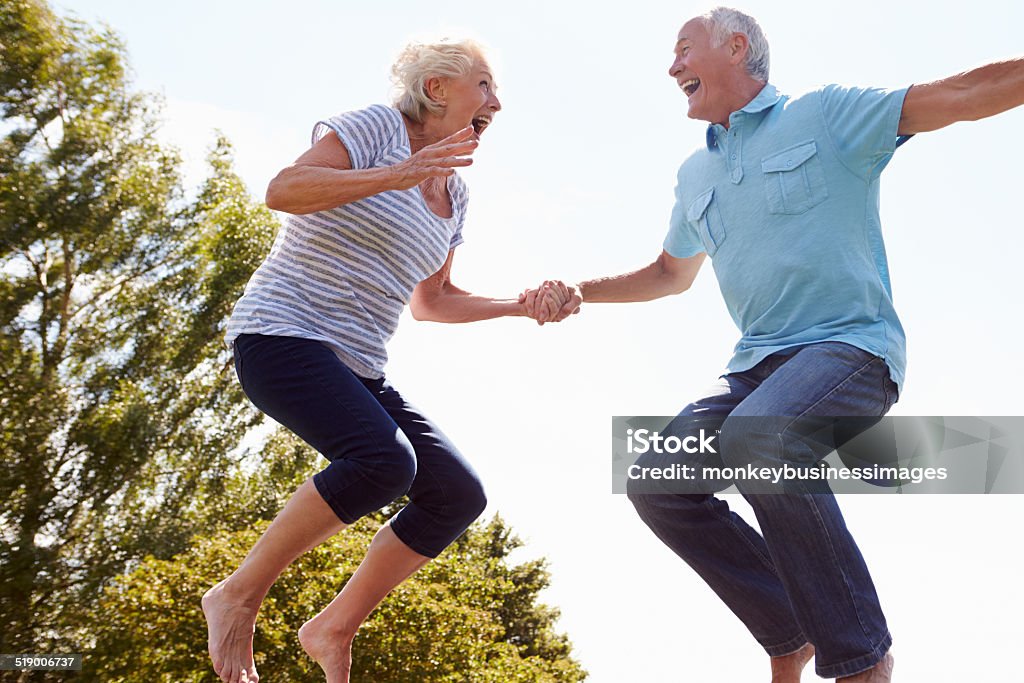 Altes Paar auf und ab springen auf Trampolin im Garten - Lizenzfrei Hochspringen Stock-Foto