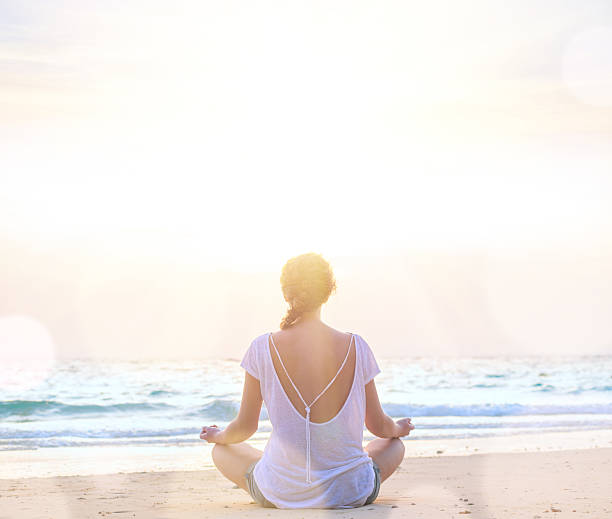 istock woman practicing yoga at sunrise beach 519011090
