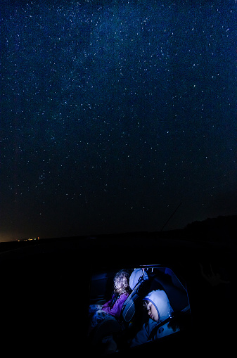 Two kids sleeping in a car with the stars and milky way above them