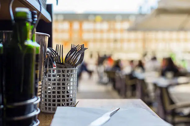 An outdoor restaurant serving tray, forks in focus, in a european style plaza.  Plaza Mayor, Spain