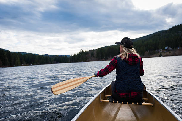 Female paddling a canoe on a prisitine mountain lake