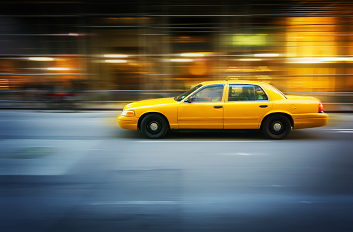 Yellow taxi speeding in Manhattan, New York City - panning motion blur technique