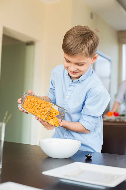 istock Smiling boy pouring corn flakes in bowl at home 519030275