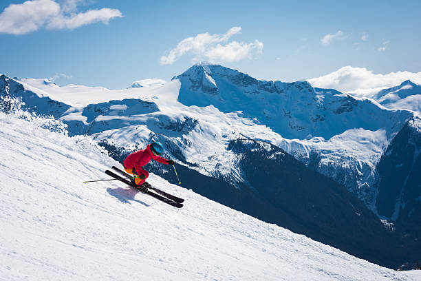 Female athlete skiing in the mountains Female skier making a turn on a bluebird day enjoying the freedom, adventure and excitement of skiing in the mountains.  Skiing is a great way to get away from it all allowing you to live in the moment while experiencing nature at its finest. whistler mountain stock pictures, royalty-free photos & images