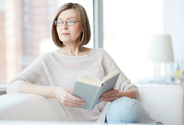 lector en su casa - women book mature adult reading fotografías e imágenes de stock