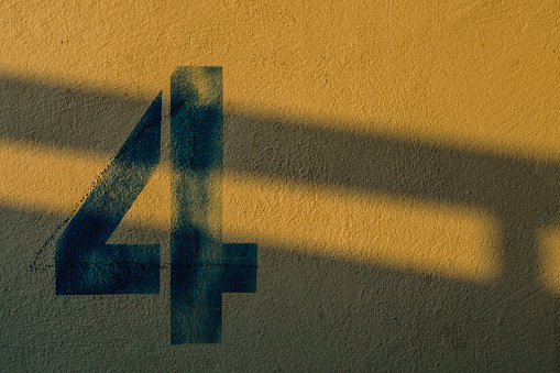 the number 4 on the wall under the shadow of the lights