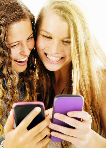 istock Two pretty girlfriends smiling at their smartphones 519040686