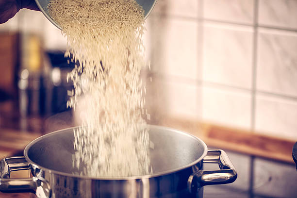 Preparing Basmati Rice for Asian Meal Preparing Basmati Rice for Asian Meal by pouring it into cooking pot of boiling water. basmati rice stock pictures, royalty-free photos & images