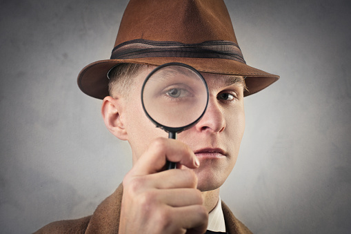 Man, with a hat, looking through a magnifying glass