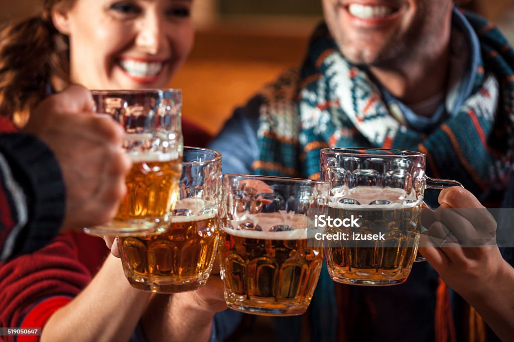 Friends toasting with beer Group of friends sitting in the pub and toasting with beer. Focus on beer glasses. Beer - Alcohol Stock Photo