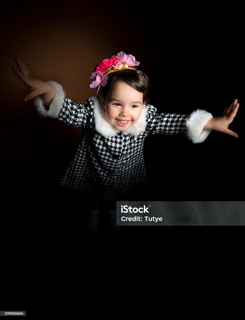 Happy beautiful little girl screaming with her hands up Happy beautiful little girl screaming with her hands up on black background, studio shot. Little girl playing Acting - Performance Stock Photo