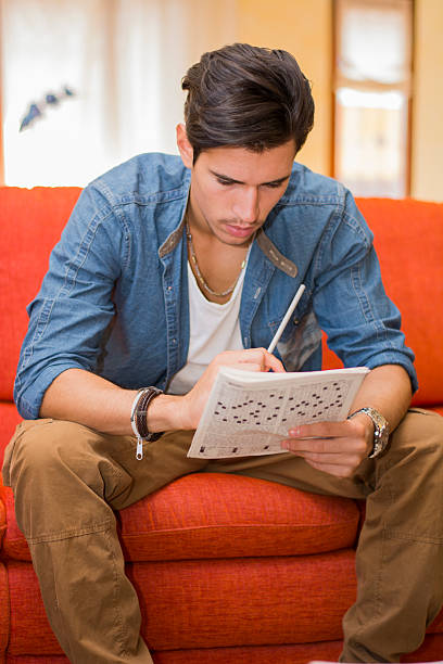 istock Young man sitting doing a crossword puzzle 519050665
