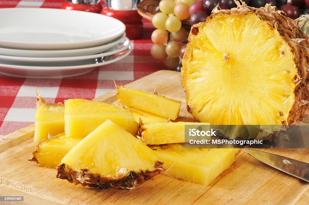 Pilneapple Sliced pineapple on a cutting board with a basket of fruit on a picnic table Basket Stock Photo