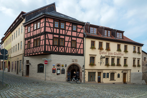 Kahla, Germany  - September 9, 2014: the Hotel zum Stadttor located in Kahla, Thuringia, Germany. This small town has a lot of old buildings and a lot of half timbered houses. In the last time many of them are restaurated, but in the city are a lof of damaged ruins too. Here the old Hotel is restaurated. In the foreground a woman on bicycle