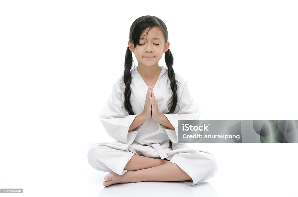 Little asian girl in white kimono meditating on white background Little asian girl in white kimono meditating on white background isolated Adult Stock Photo