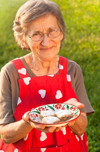 cute grandmother holding a plate with apple pie stock photo