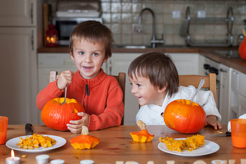 Two adorable boys, preparing jack o lantern for Halloween at home