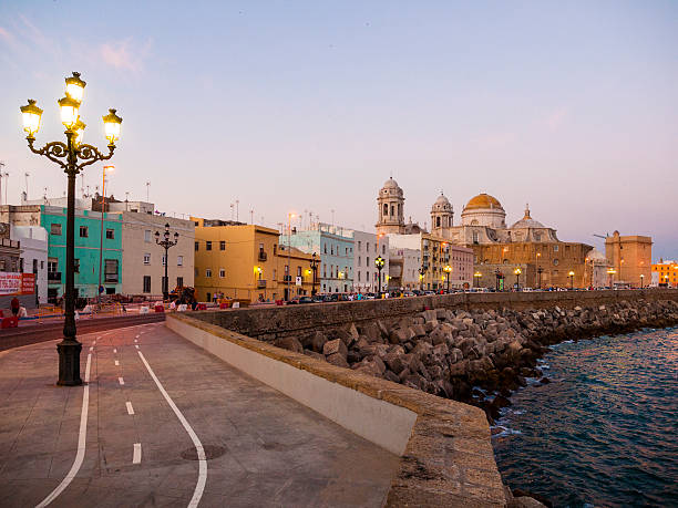 Cadiz, Spain - July 5, 2010: Seaside neighborhood in La Caleta in Cadiz, Spain during twilight. People can be seen walking around by the street.