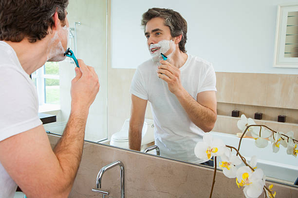 man shaving at bathroom mirror - shaving men shaving cream mirror imagens e fotografias de stock