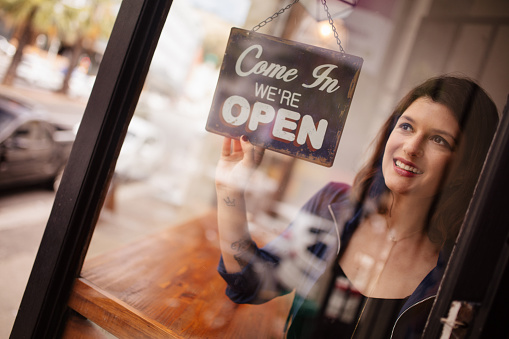 Mujer de negocios dueño de giro de señal de puerta de apertura en la cafetería photo