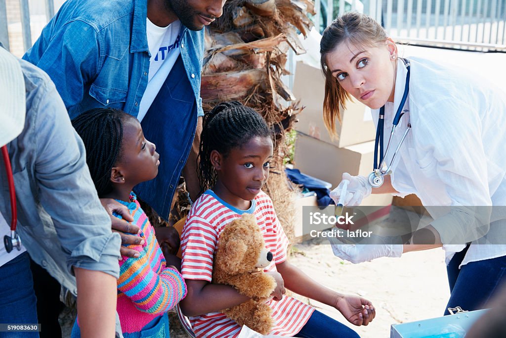 Providing free vaccinations to her community Shot of a volunteer nurse giving injections to underprivileged kids Poverty Stock Photo