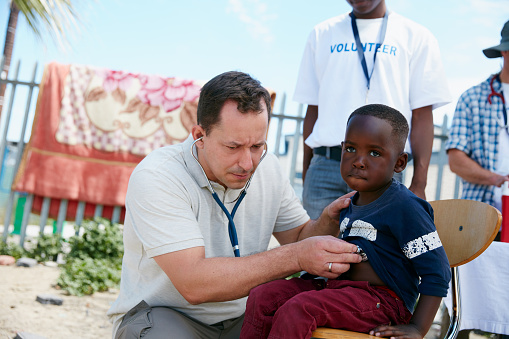 Shot of a volunteer doctor examining a young patient with a stethoscope at a charity event