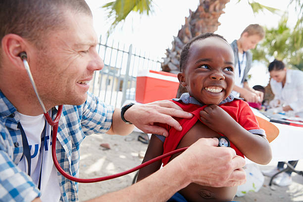 That tickles! Shot of a volunteer doctor giving checkups to underprivileged kids charity and relief work stock pictures, royalty-free photos & images