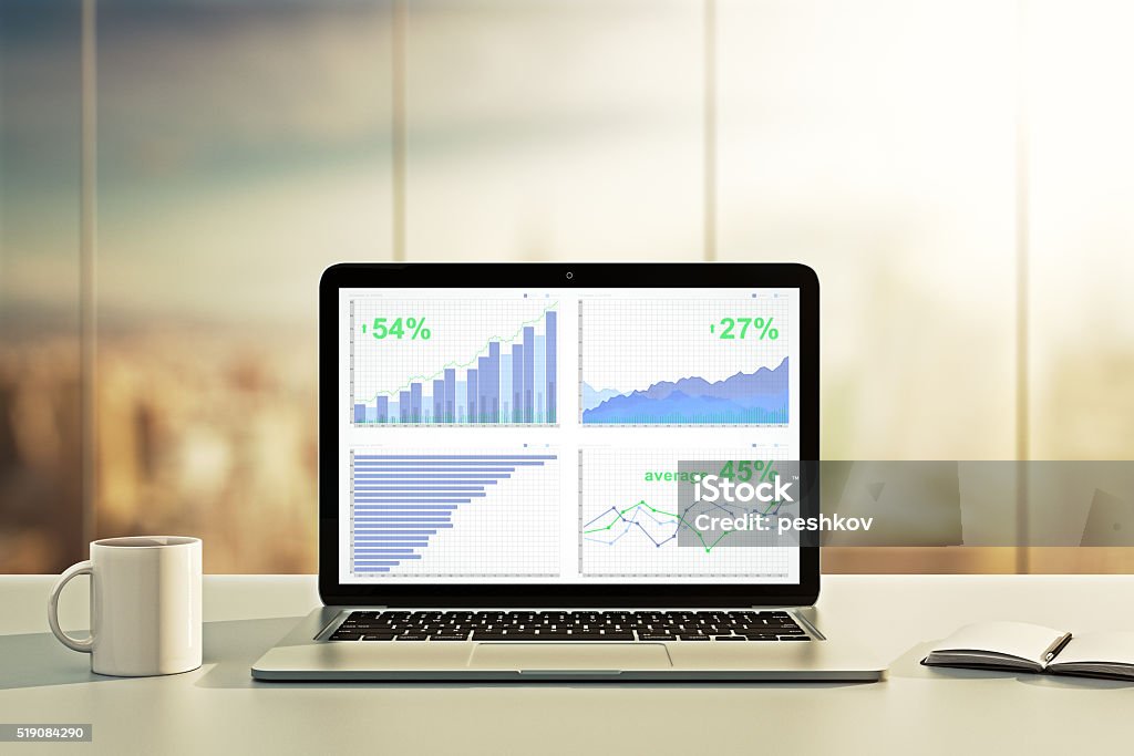 Ordenador portátil con estadísticas financieras de escritorio - Foto de stock de Ordenador portátil libre de derechos