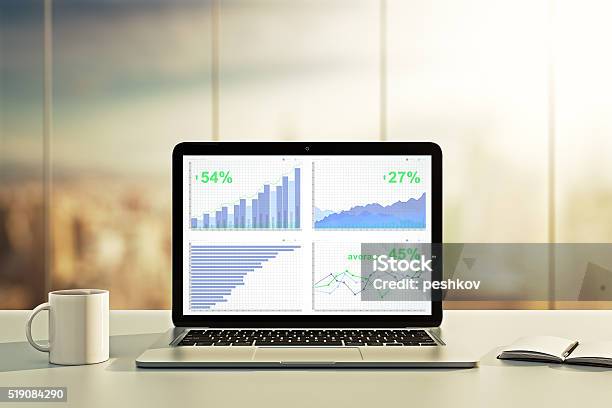 Laptop With Financial Statistics On A Desktop Stock Photo - Download Image Now - Laptop, Table, Growth