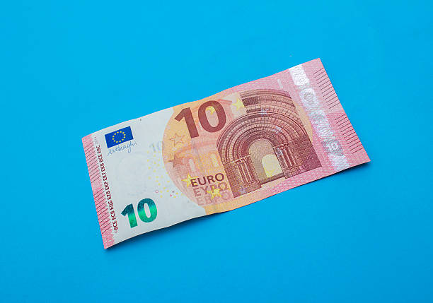 High angle view of single ten euro banknote over blue background. Horizontal composition. Image taken in studio over isolated on blue and developed from RAW format.