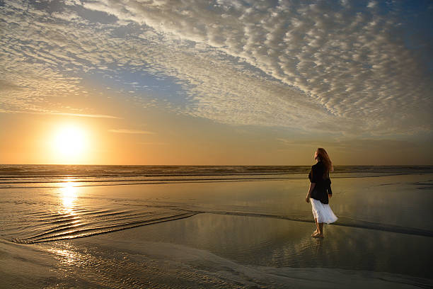 istock Woman walking on the beach at sunrise. 519090140