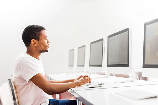 Side view of young African American man using computer in a computer lab.